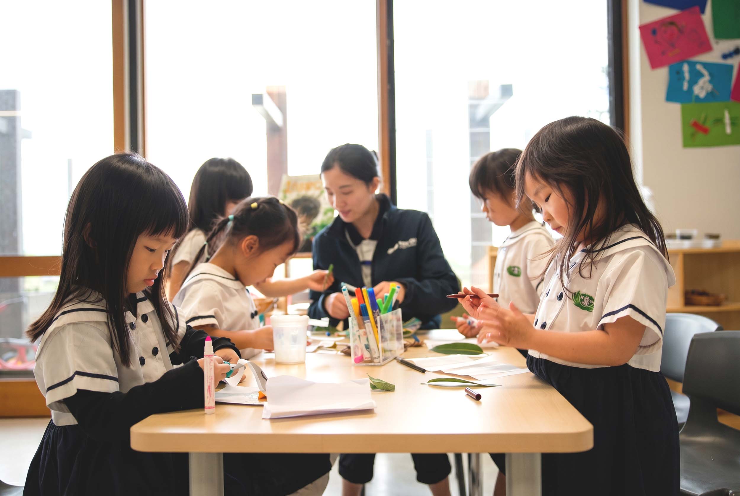 Tzu Chi classroom, children sitting round table with educator doing crafts